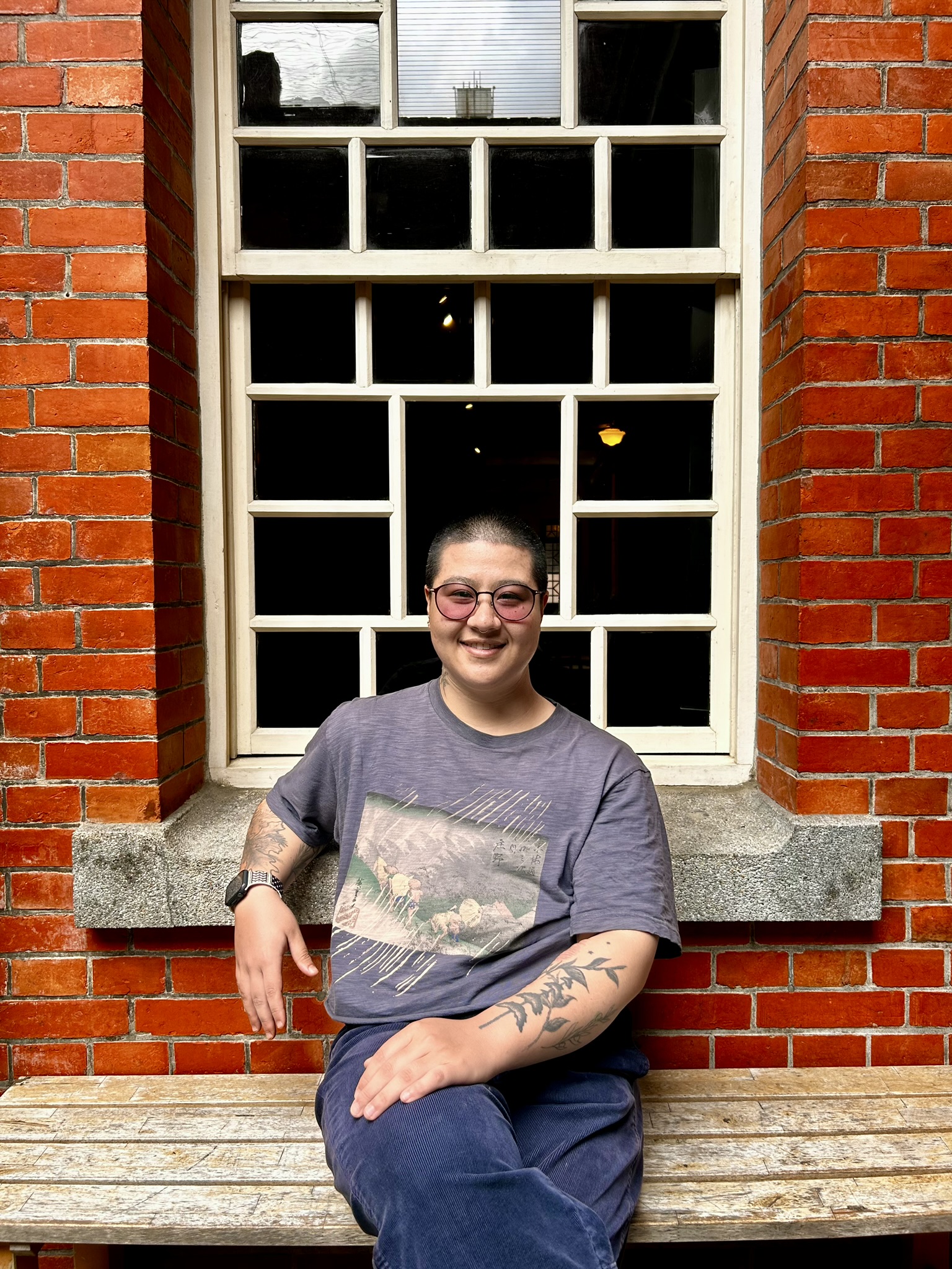 Maria sitting in front of an old window surrounded by red brick.